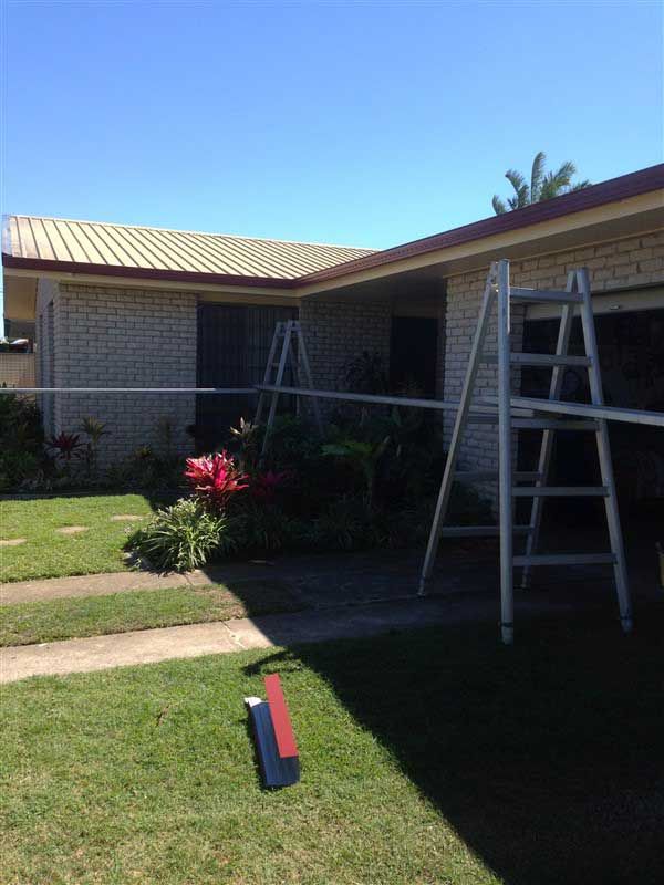 Ladders Against a Brick House — Vision Roofing Fascia & Gutter in Hervey Bay, QLD