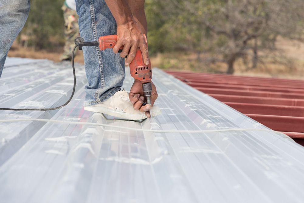 Person Using a Power Drill to Install Metal Roofing on a Structure — Vision Roofing Fascia & Gutter in Burrum Heads, QLD