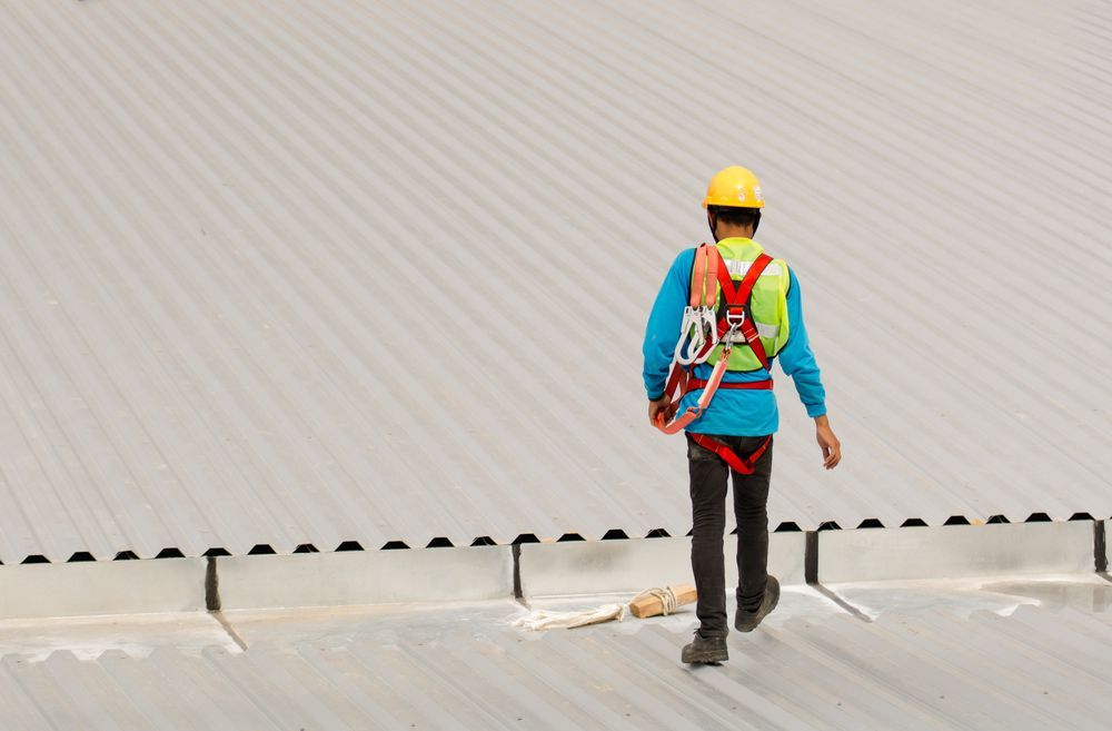 Worker on a Metal Roof, Wearing a Hard Hat and Safety Harness — Vision Roofing Fascia & Gutter in Poona, QLD