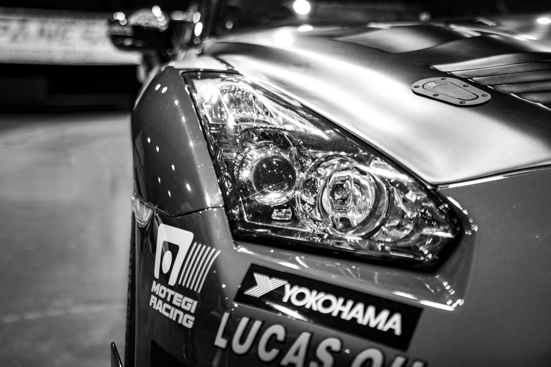 Close-up of a race car headlight and front, with sponsor stickers in black and white.