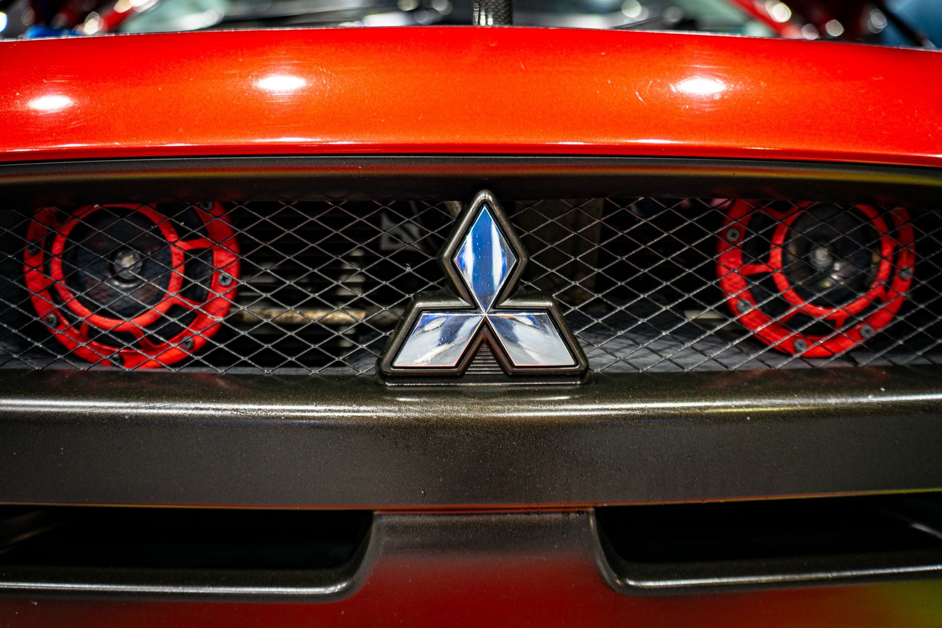 Red Mitsubishi car front with logo, grill, and two red speakers.