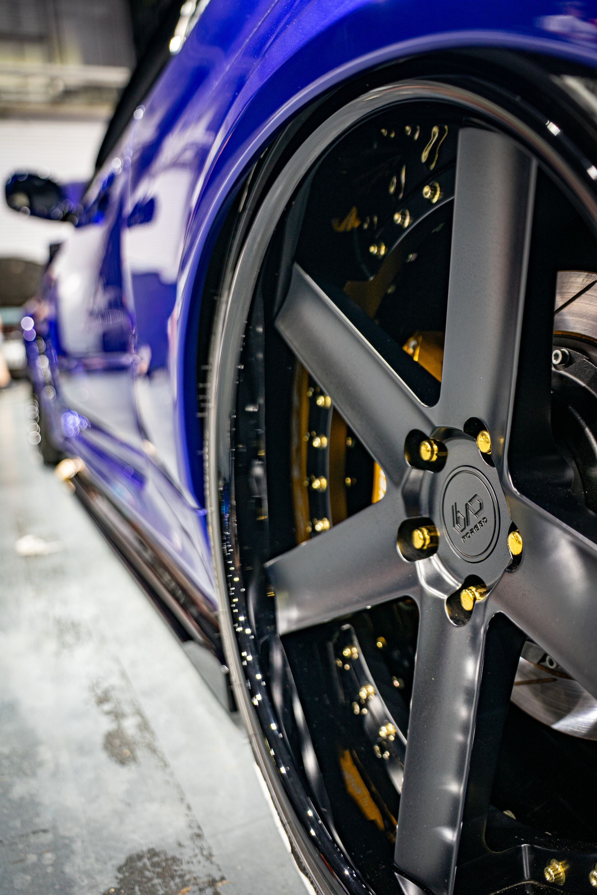 Close-up of a blue sports car wheel with black spokes and gold accents.