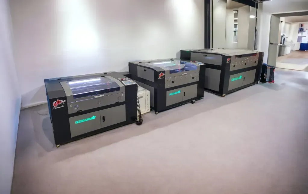 Three large, gray and black industrial printers in a bright room.