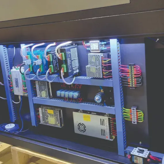 Control panel with various electrical components, wires, and power supplies.