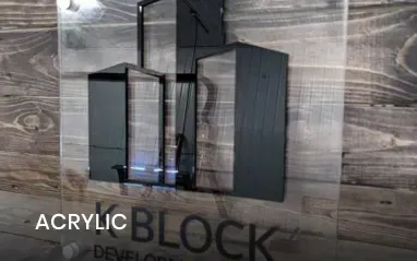 Acrylic sign featuring black building shapes, on a wooden background with