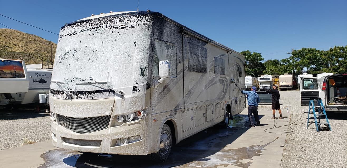 A rv is covered in foam in a parking lot.