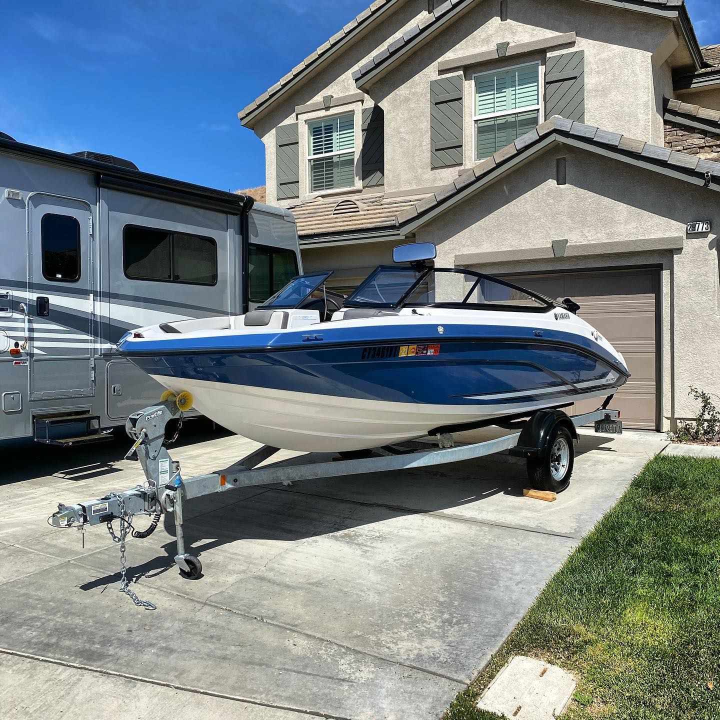 A blue and white boat is parked in front of a house.