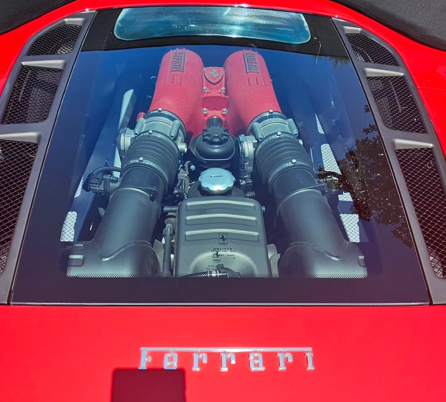 The engine of a red ferrari is visible through the windshield