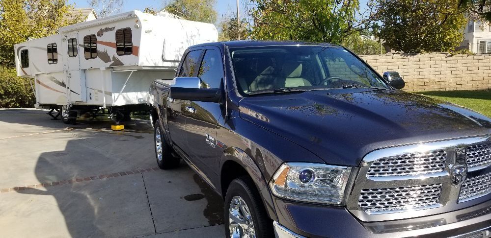A pickup truck is towing a trailer in a driveway.
