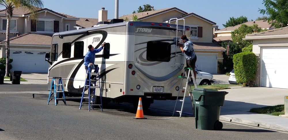 Two men are working on a rv in a residential neighborhood