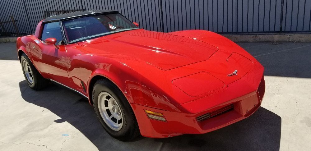 A red corvette is parked in front of a building.