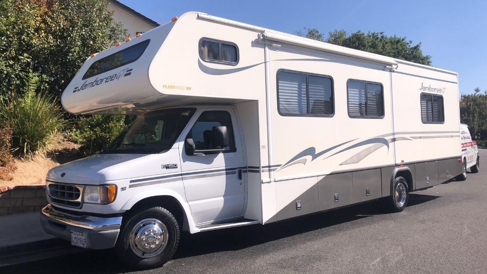 A white rv is parked on the side of the road.