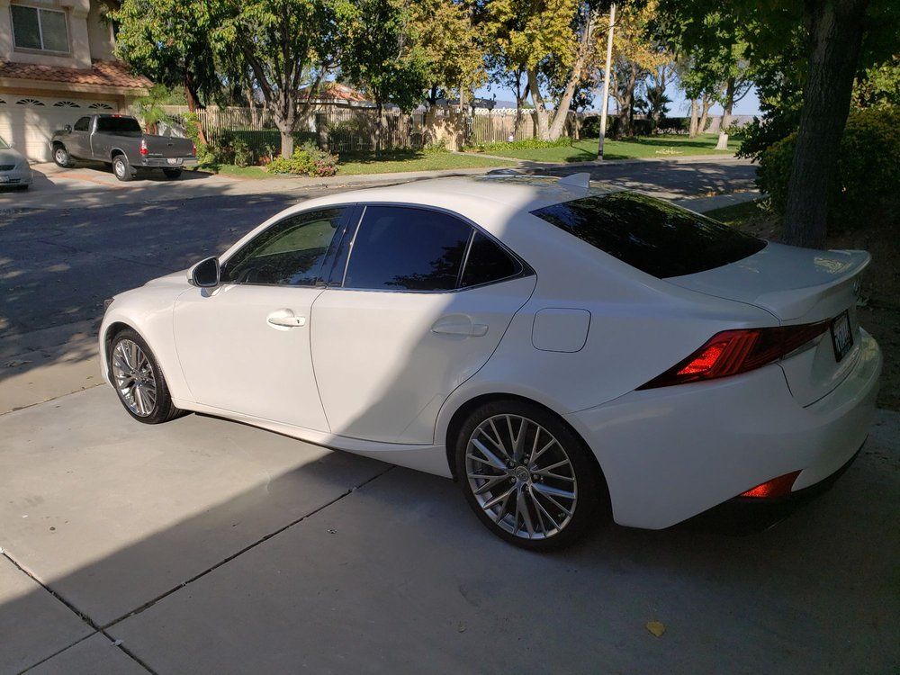 A white car is parked in a driveway in front of a house.