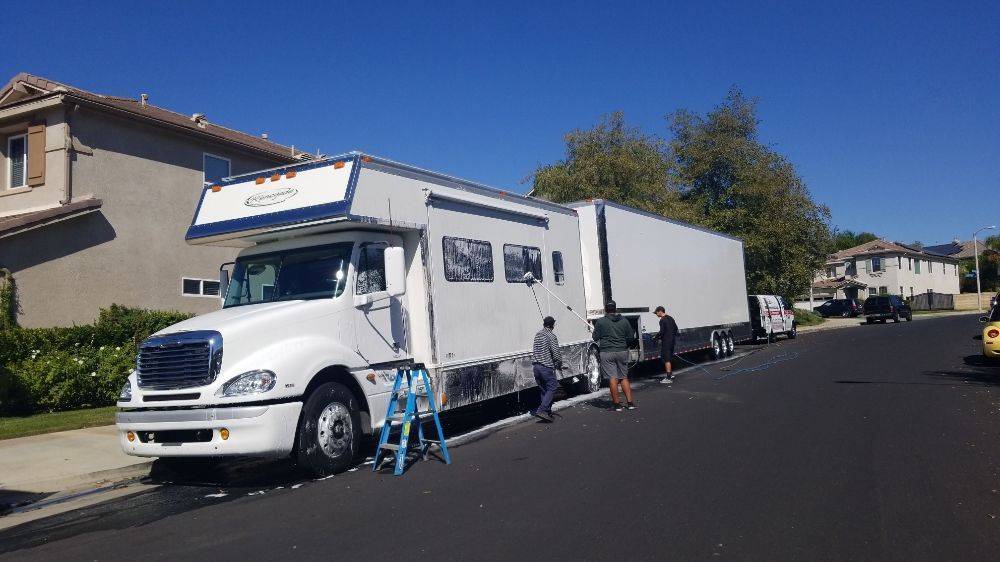 A large white truck is parked on the side of the road next to a house.