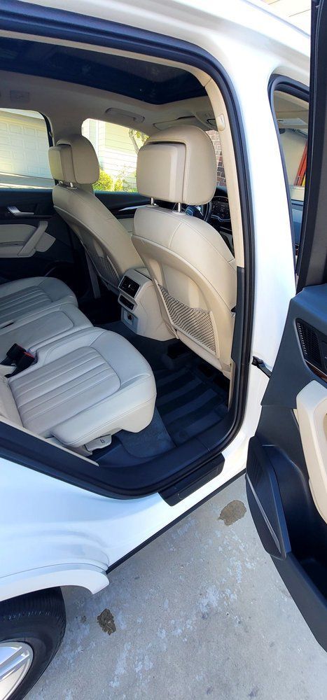 The back seat of a white car with the door open.