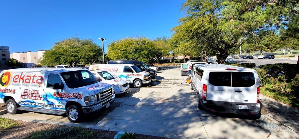 A row of white vans are parked in a parking lot.