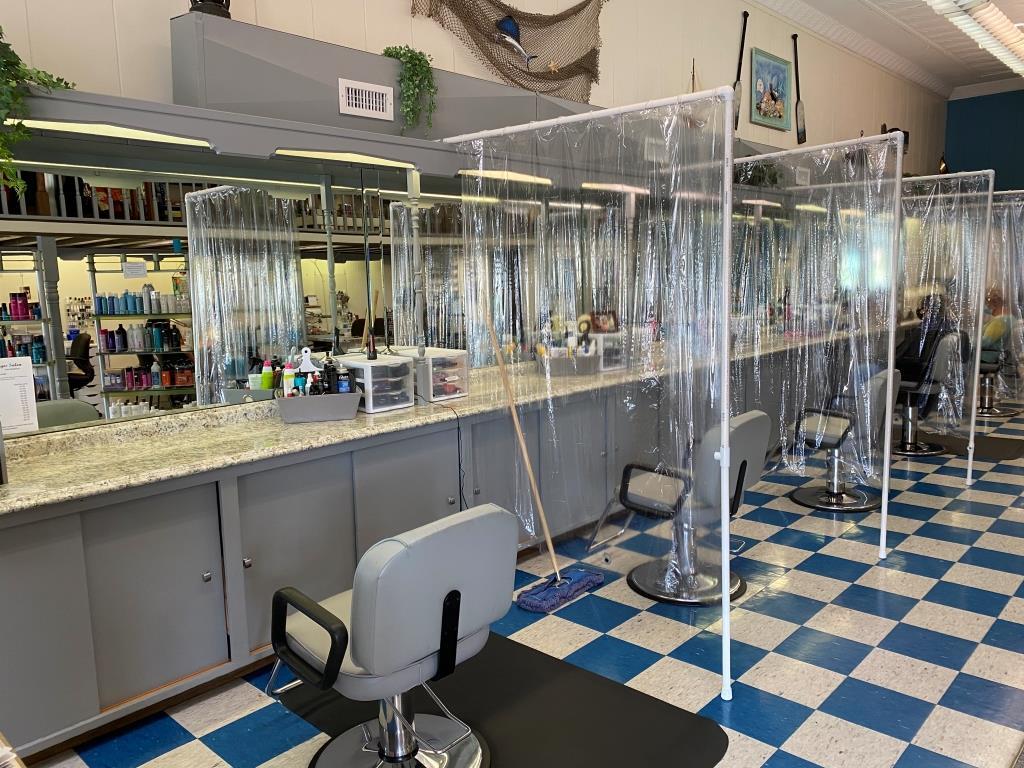 A barber shop with clear plastic dividers between the chairs