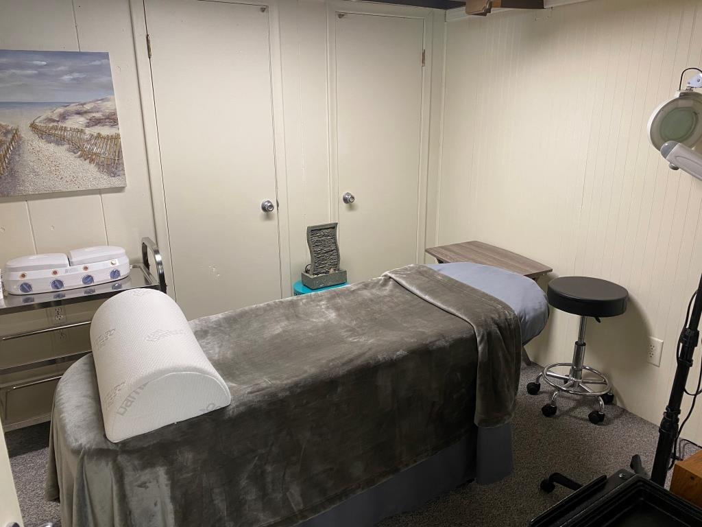 A massage table in a room with a painting on the wall.