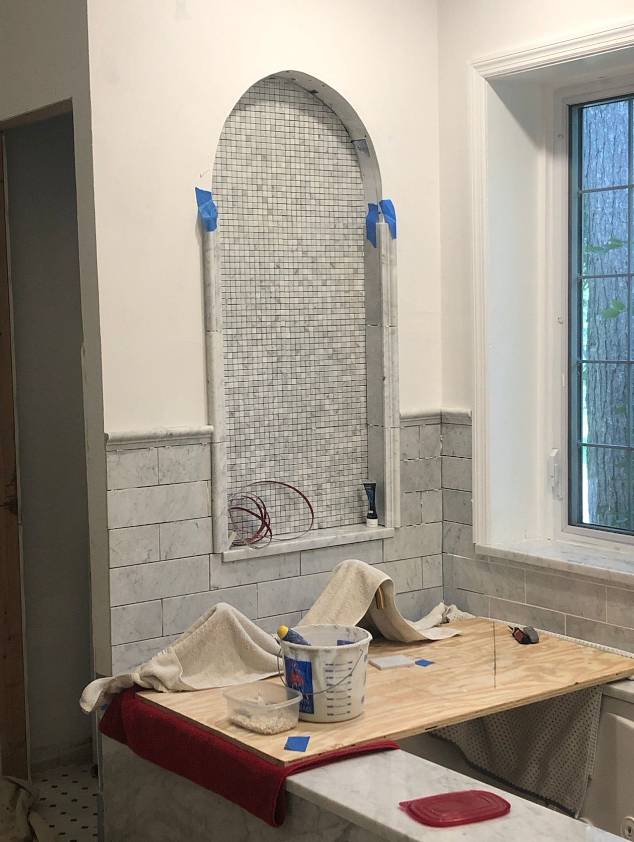 Bathroom under renovation with an arched niche being tiled.
