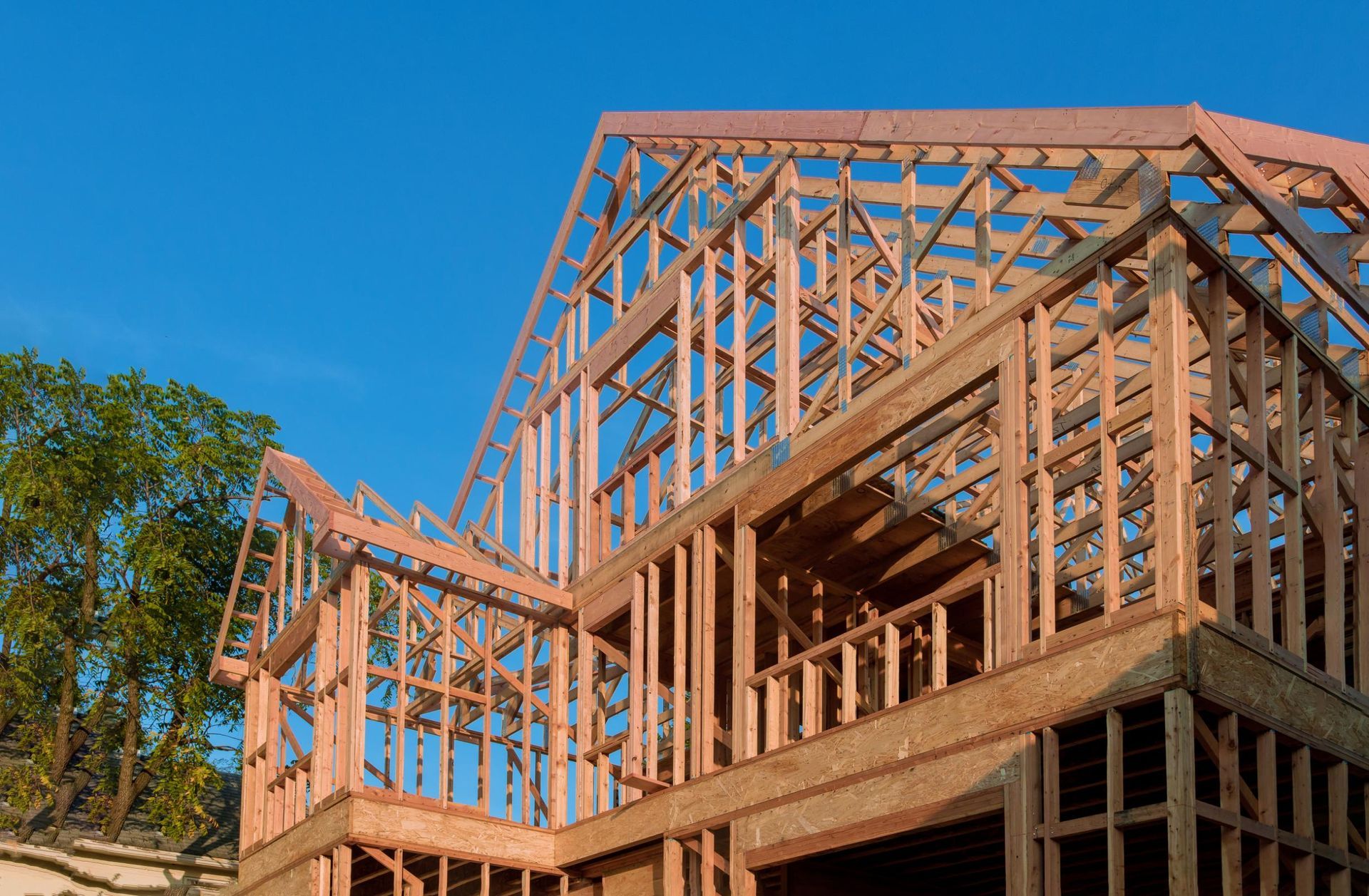 Wooden framework of a house under construction against a blue sky.