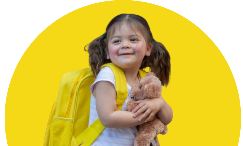 A little girl with a yellow backpack is holding a teddy bear.
