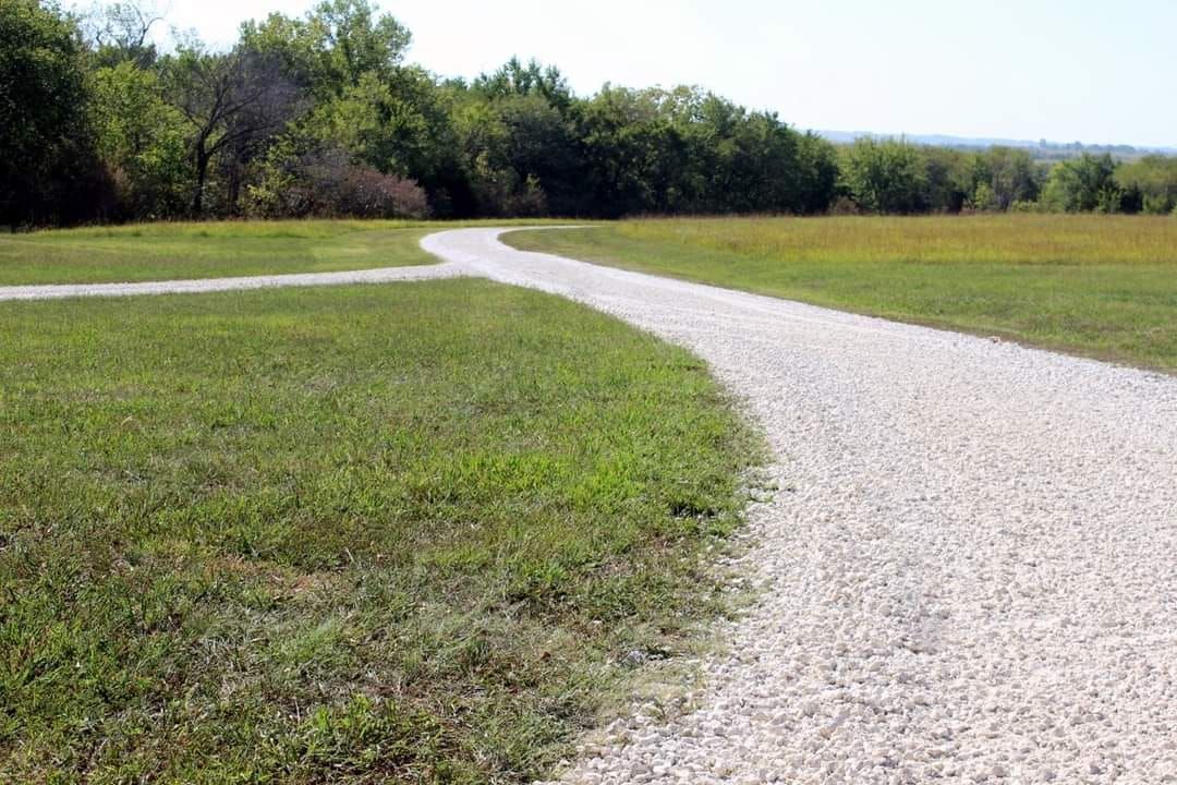 A gravel path going through a grassy field.
