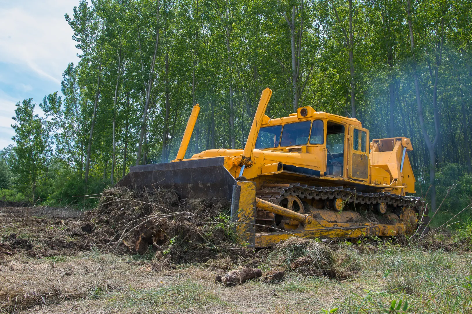 A yellow bulldozer is moving dirt in a field.