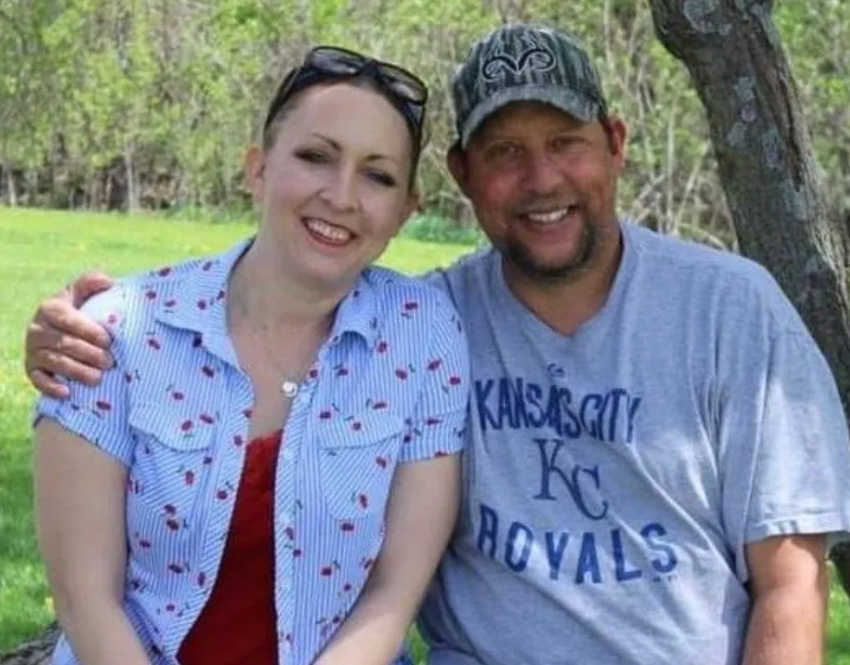 A man and a woman are posing for a picture and the man is wearing a kansas city royals shirt