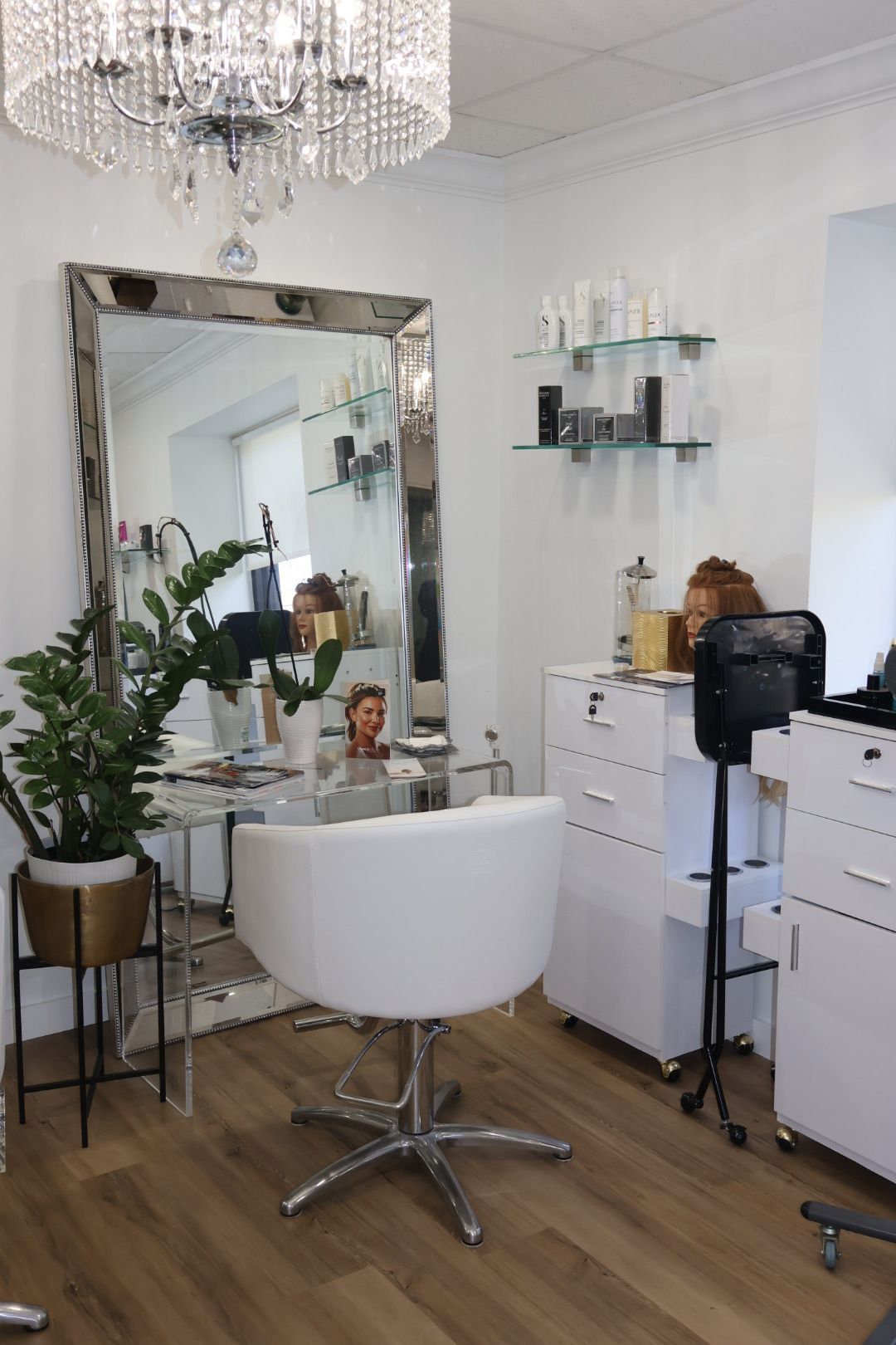 A hair salon with a large mirror and a white chair.