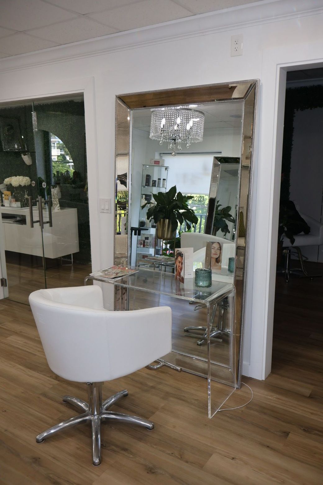 A white chair is sitting in front of a large mirror in a salon.