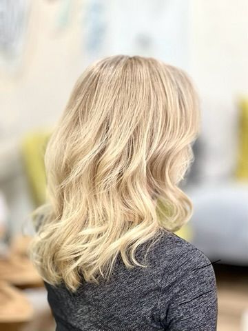 A woman with blonde hair is wearing a gray shirt.