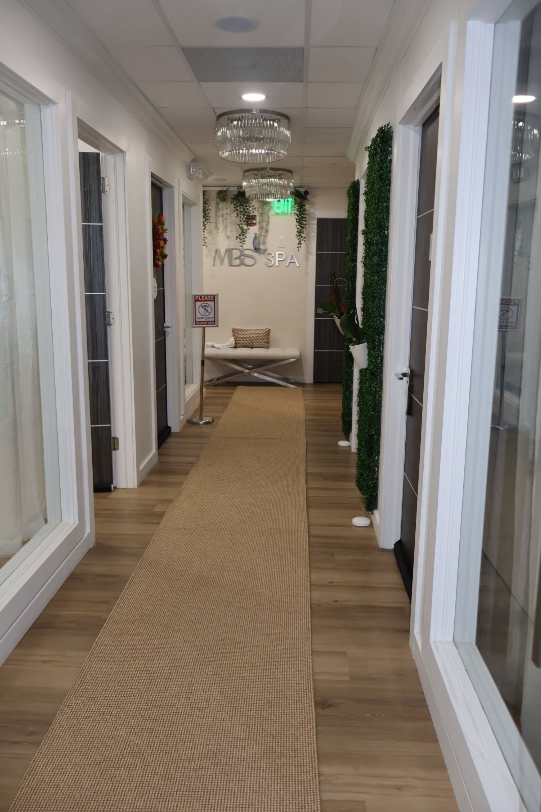 A long hallway in a building with a carpeted floor and lots of windows.