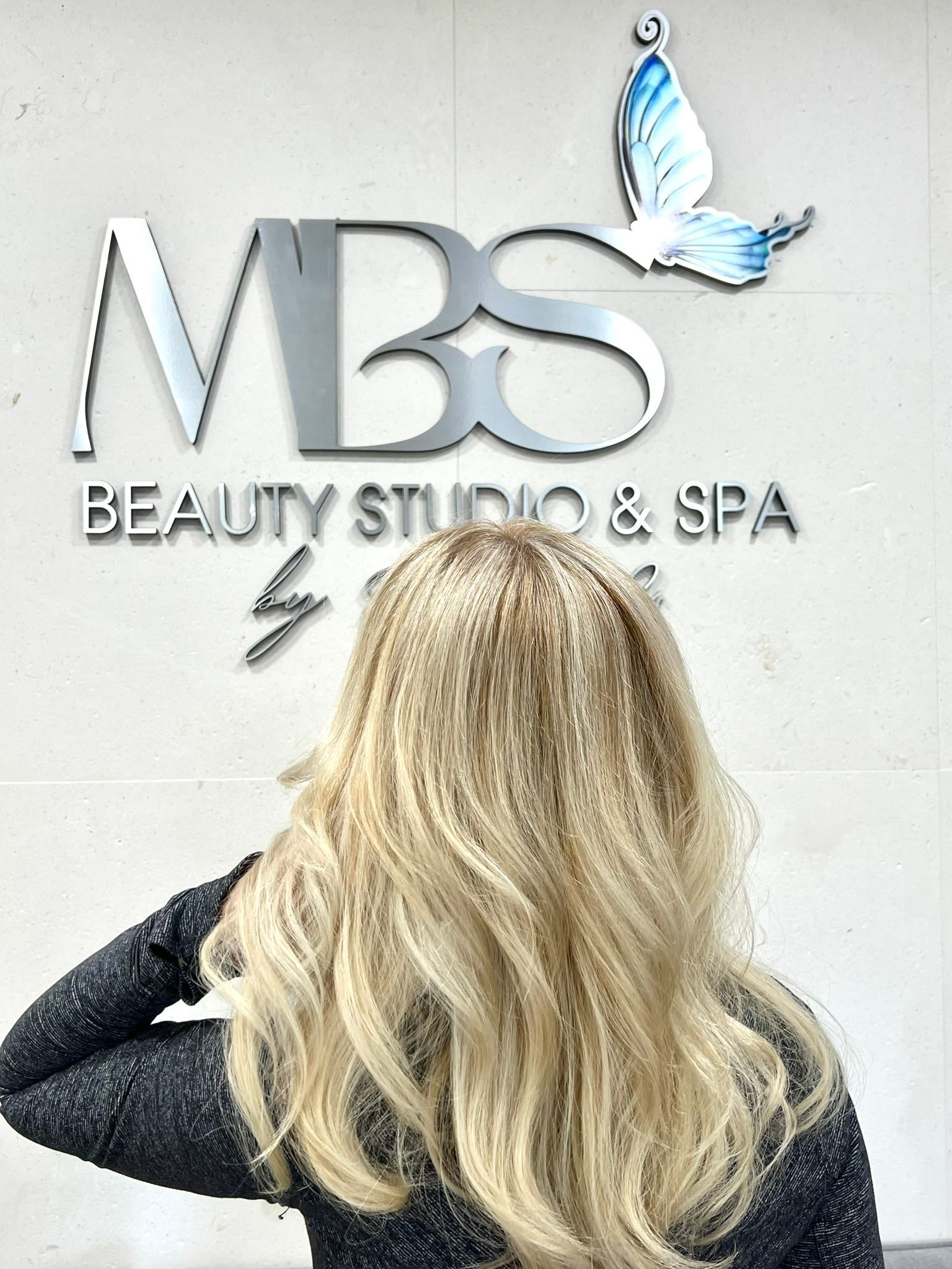 A woman with long hair is sitting in a chair in a salon.