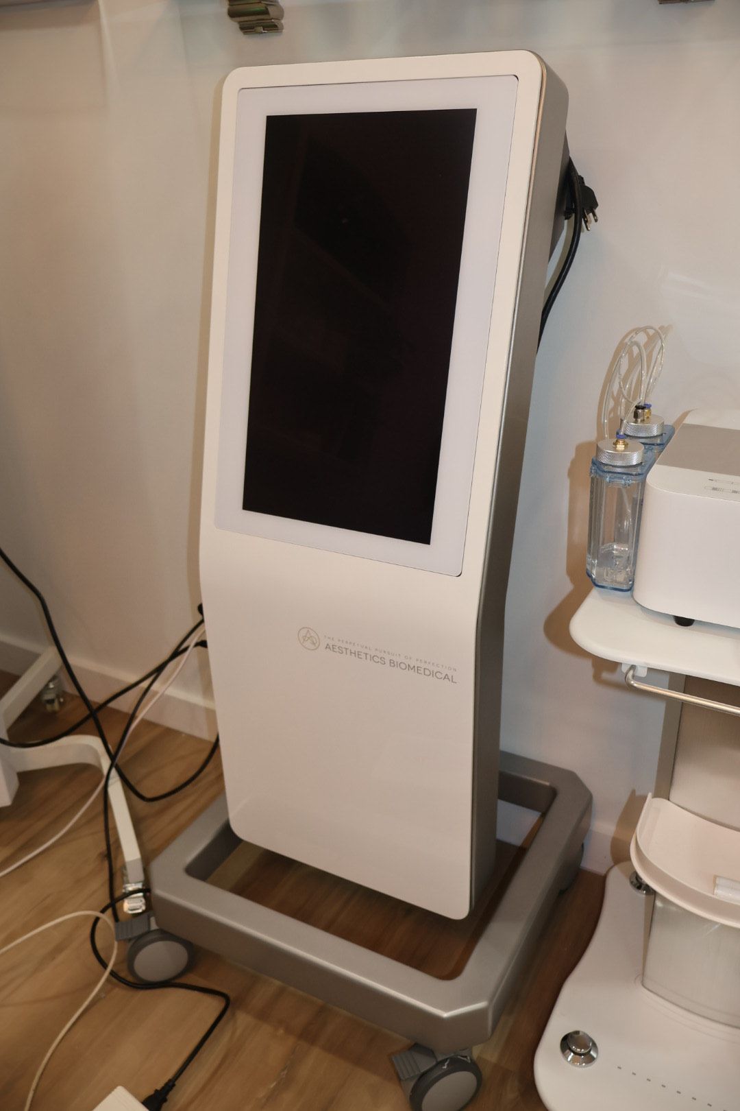 A white kiosk with a black screen is sitting on a wooden floor