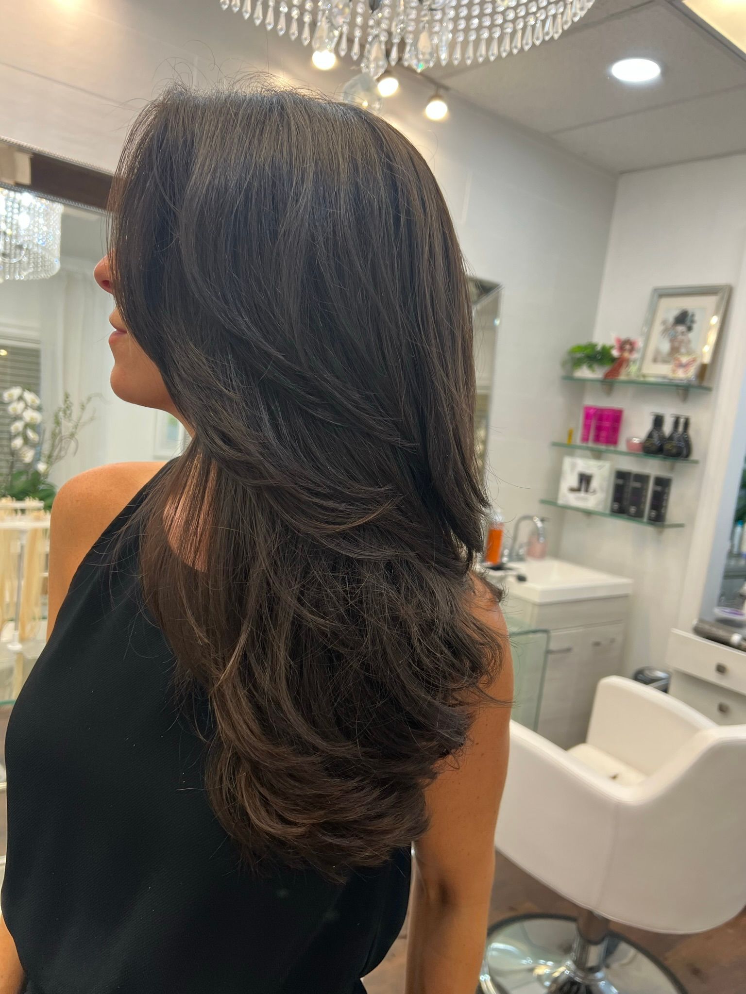 A woman with long hair is sitting in a chair in a salon.