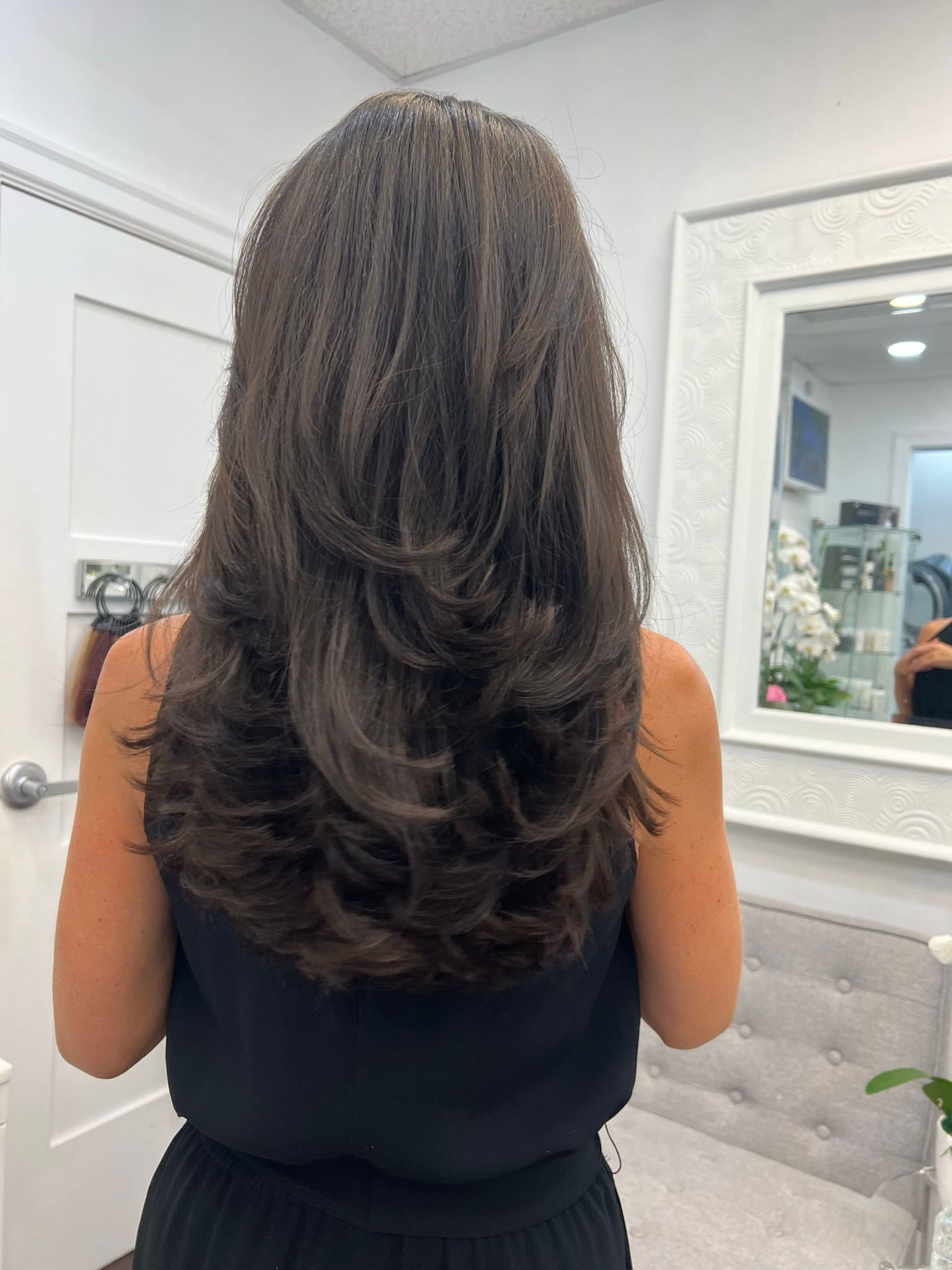 A woman with long brown hair is standing in front of a mirror.
