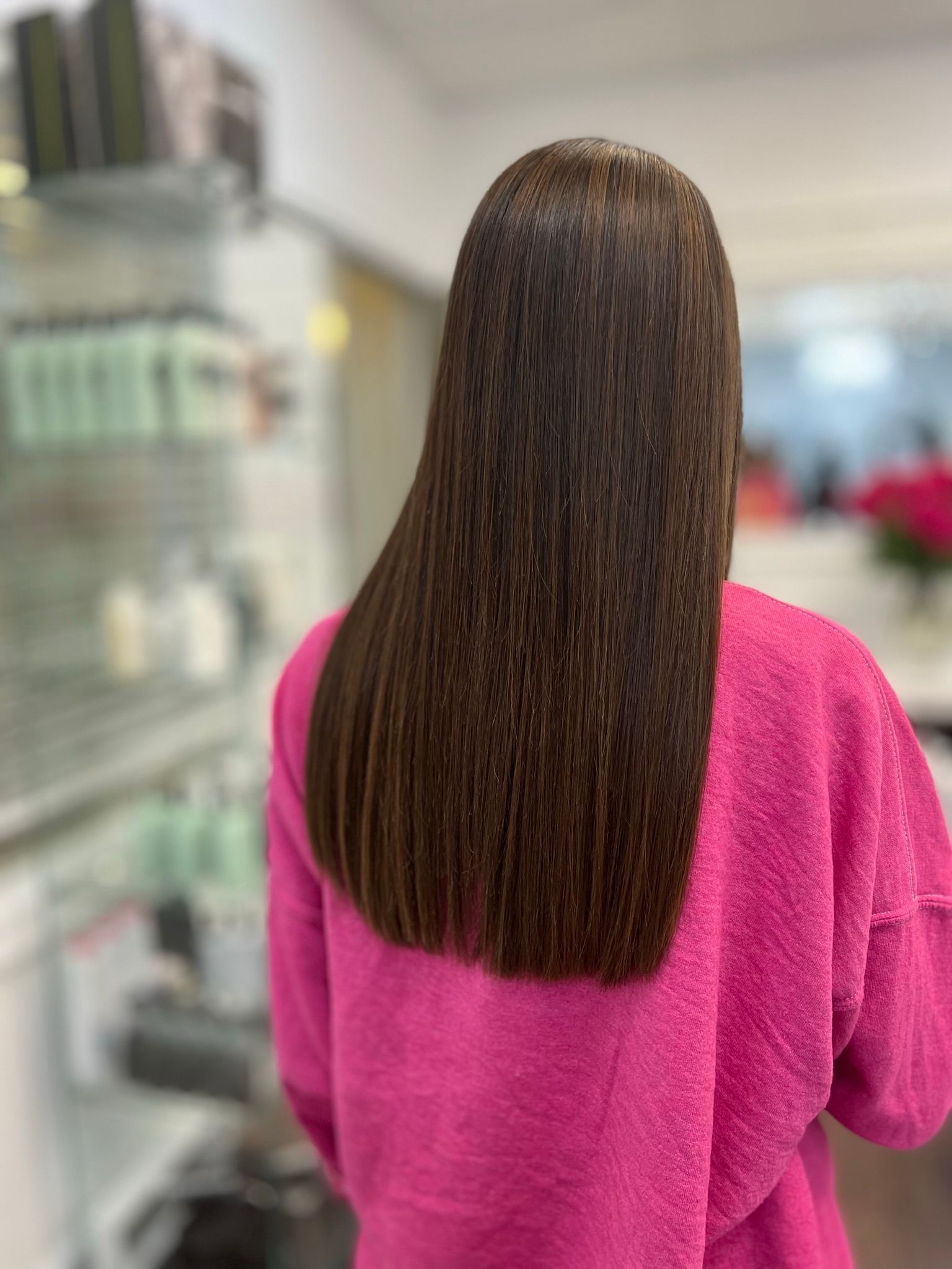 The woman is wearing a pink sweater and has long hair.