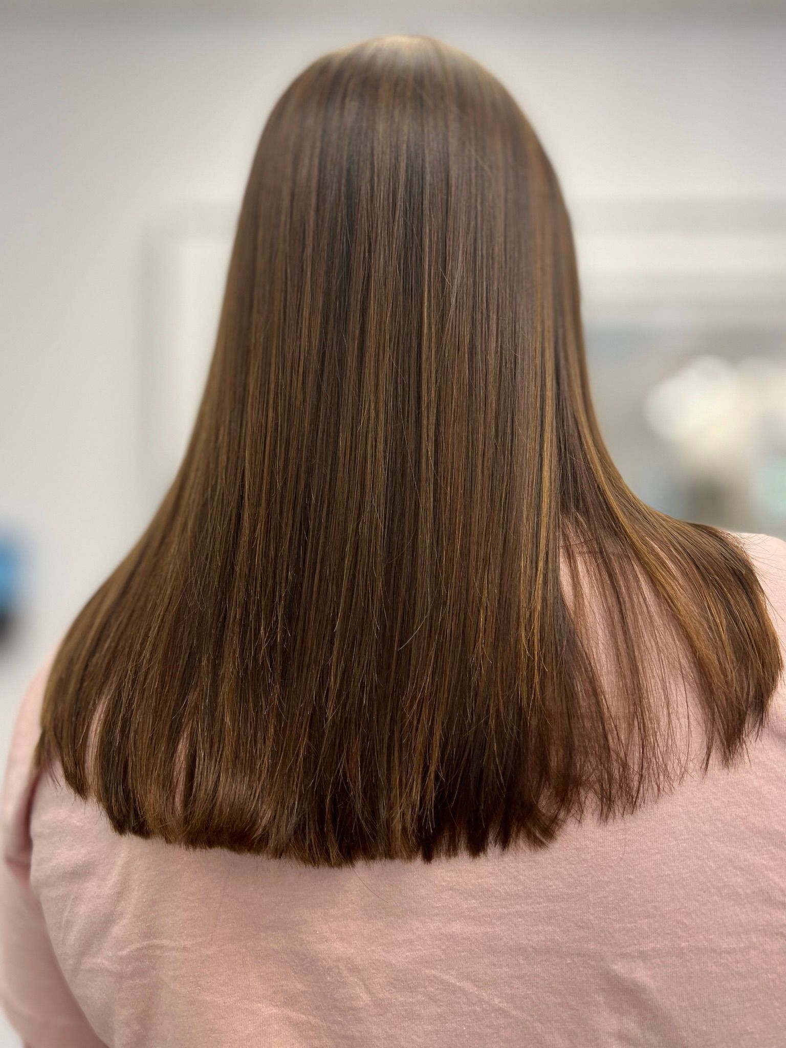 A woman with long brown hair is wearing a pink sweater.