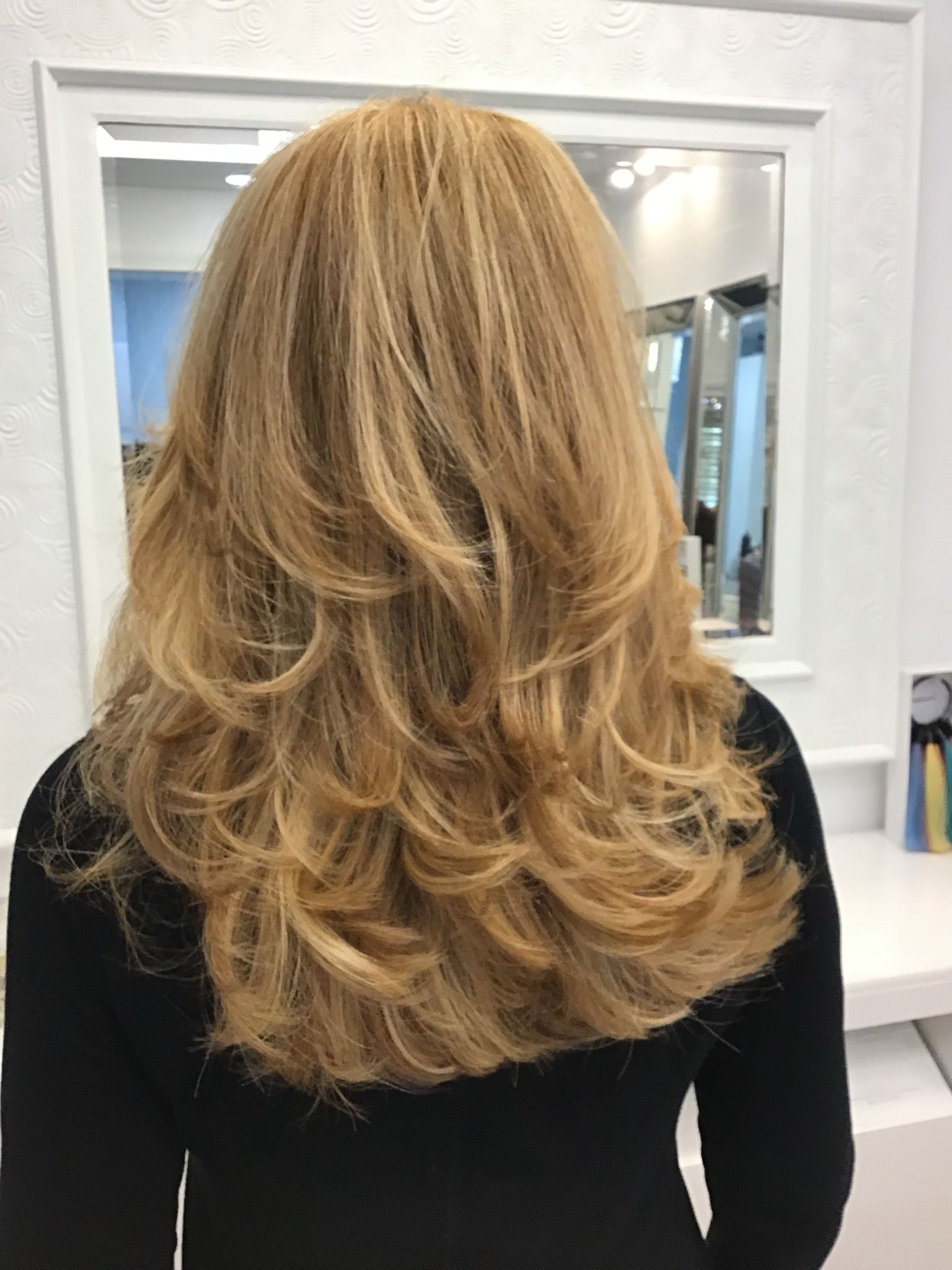 A woman with long blonde hair is standing in front of a mirror.