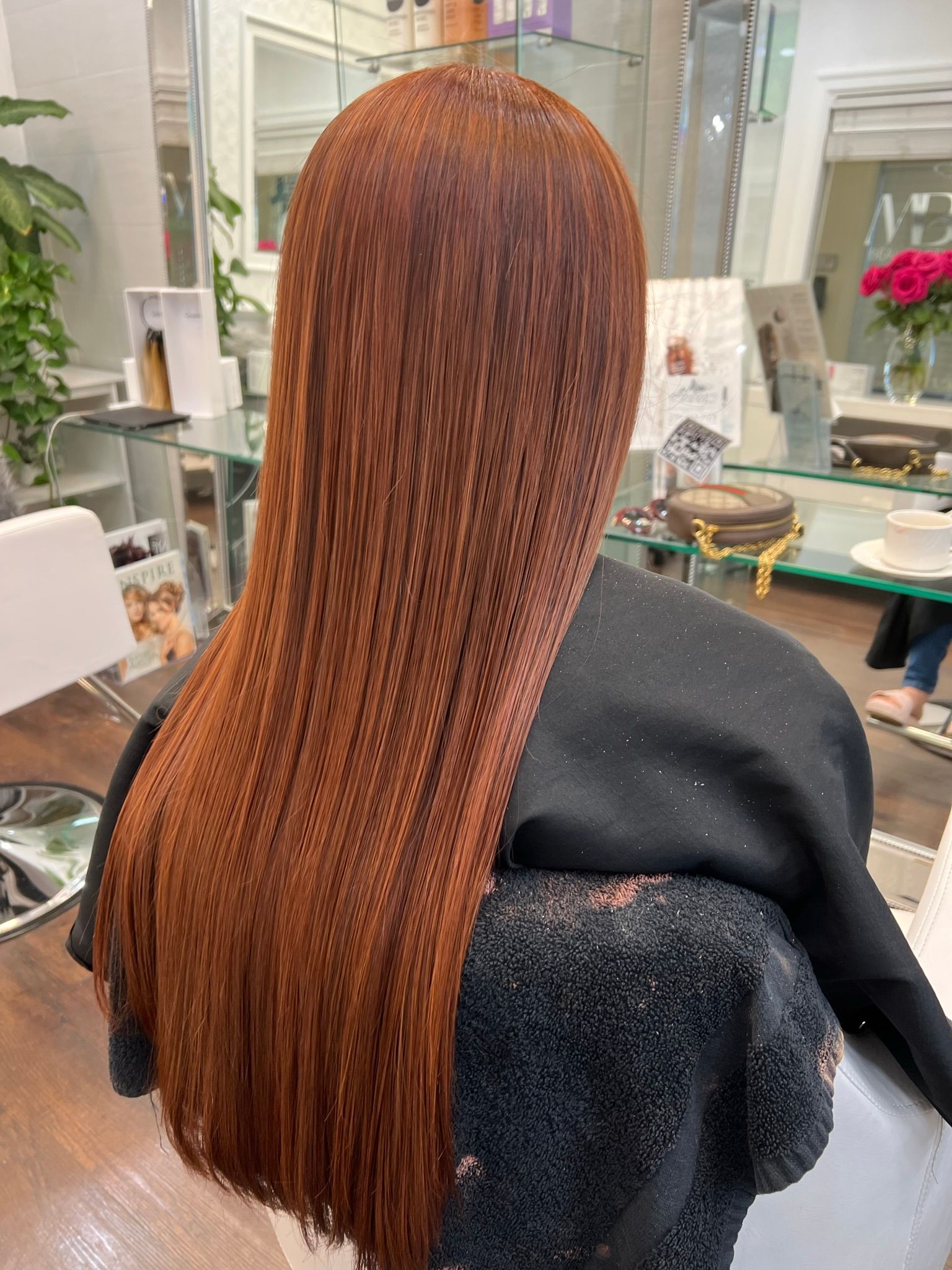 A woman with long red hair is sitting in a chair in a salon.