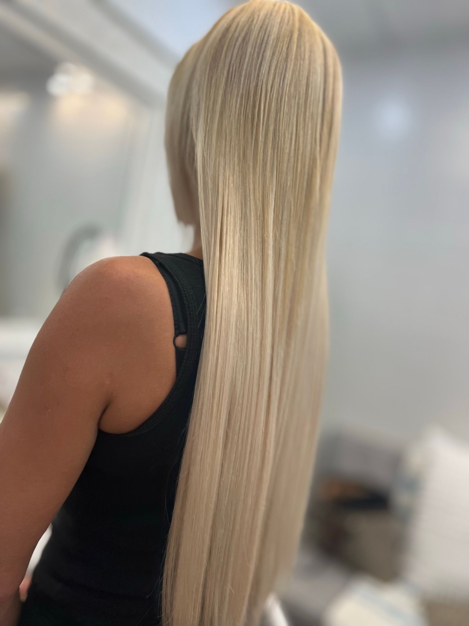 A woman with long blonde hair is wearing a black tank top.