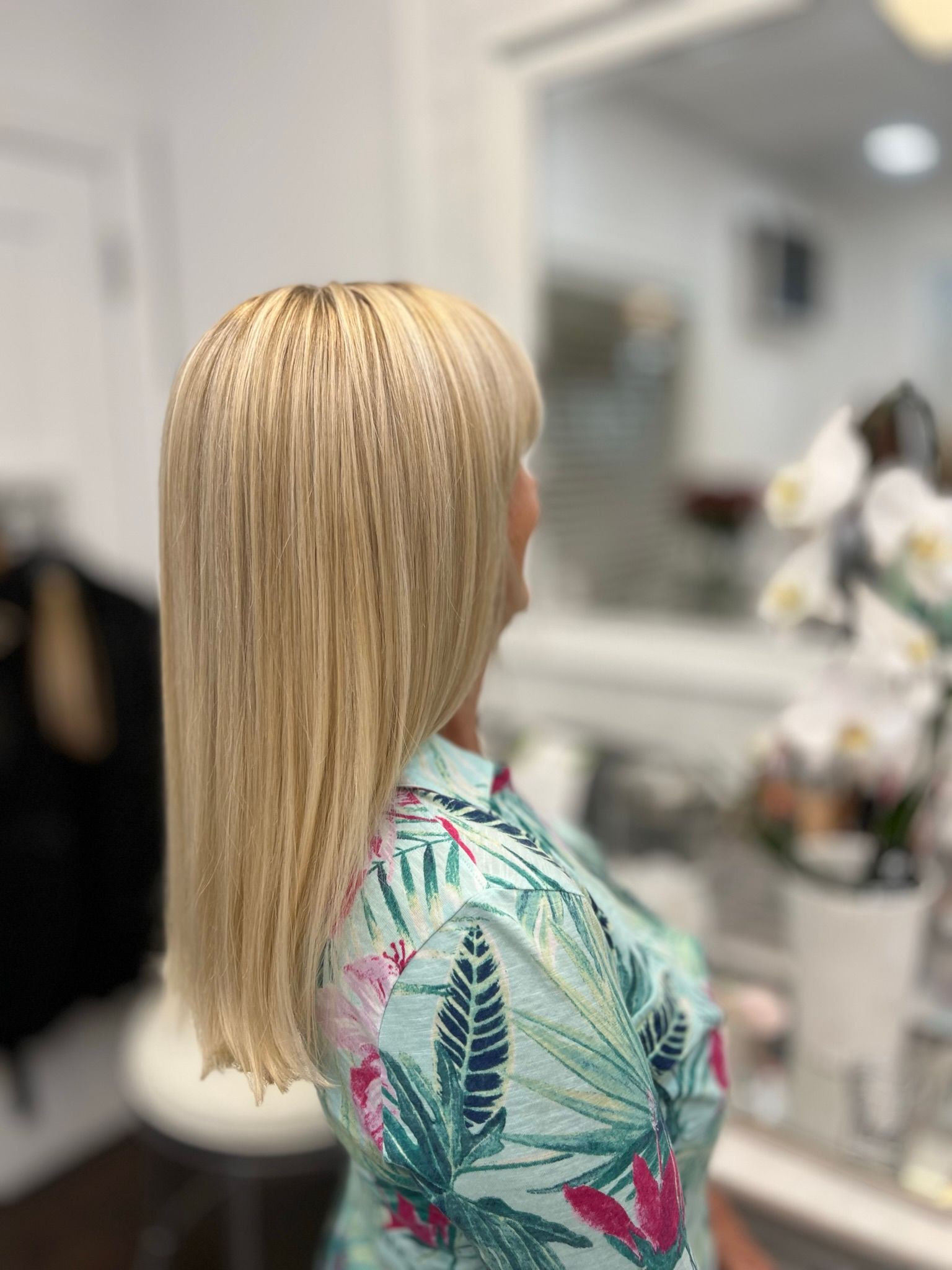 A woman with long hair is standing in a room wearing jeans and a white shirt.