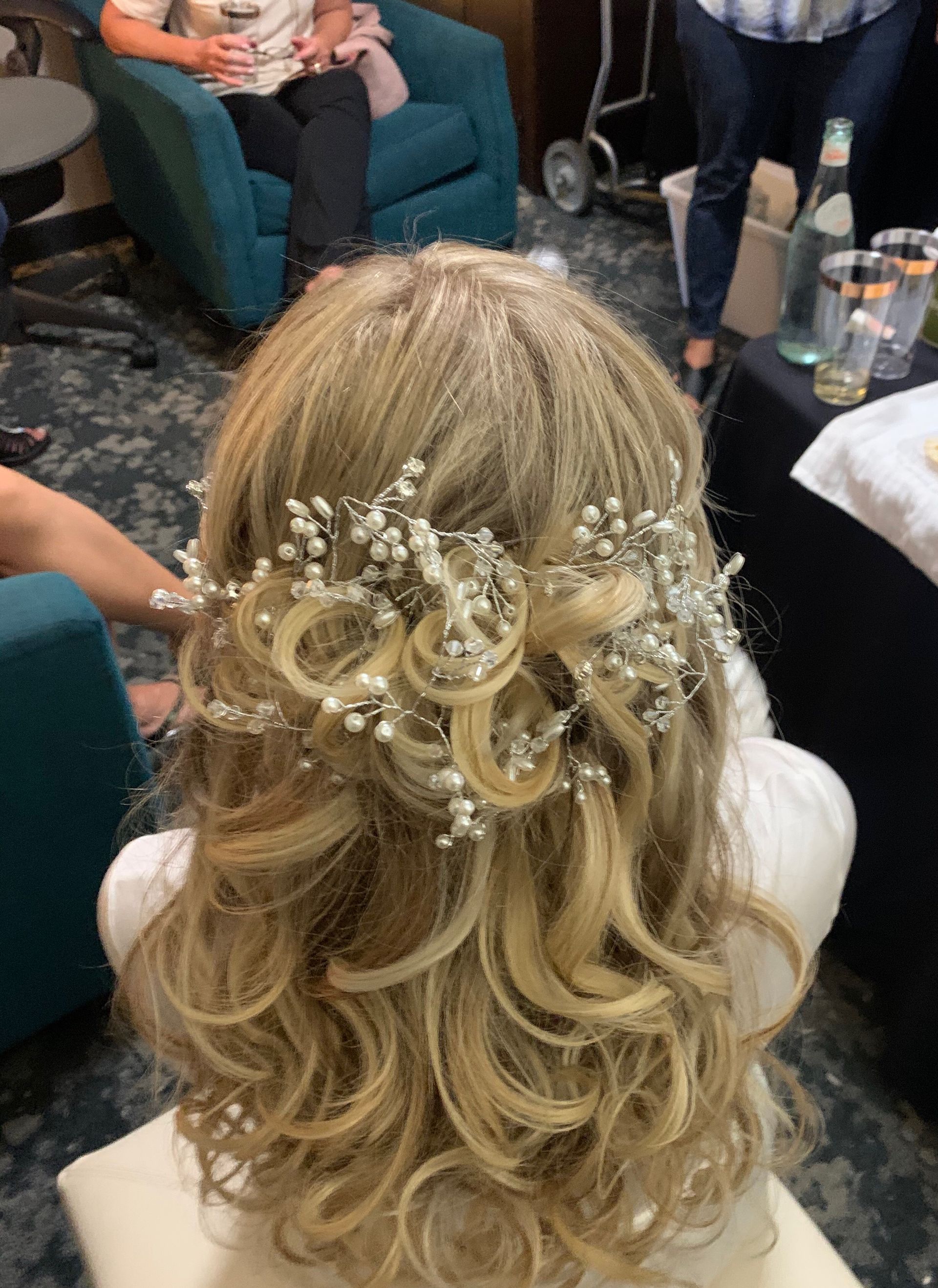 A woman with blonde hair and baby 's breath in her hair is sitting in a chair.