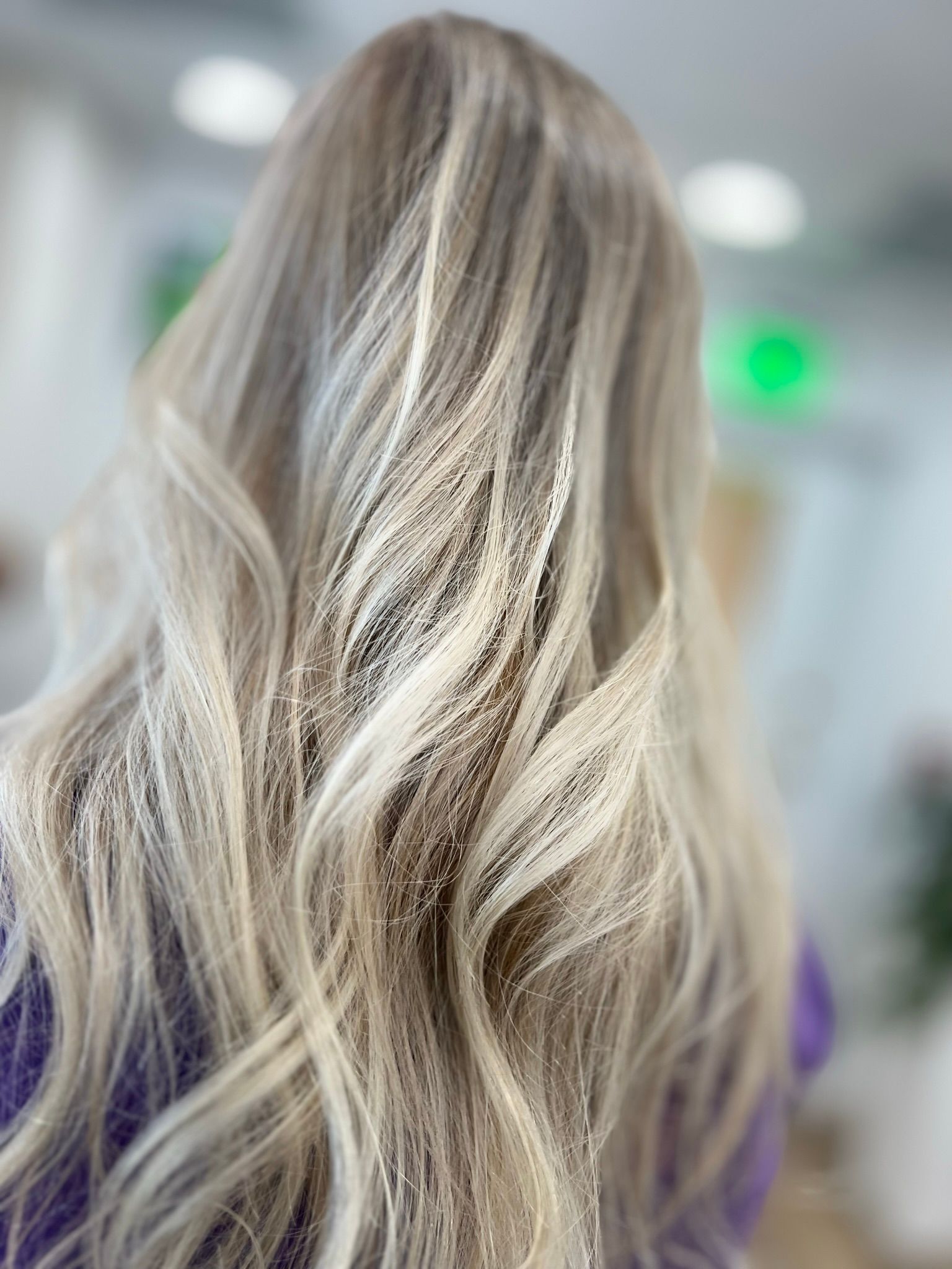 A woman with long blonde hair is wearing a purple shirt.