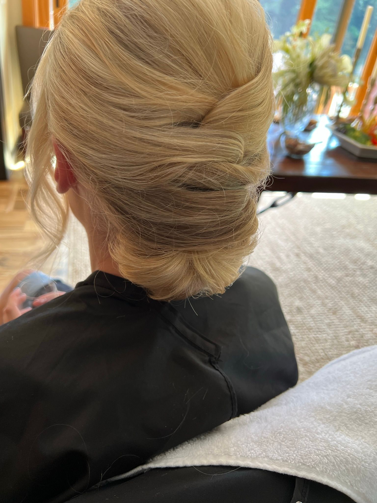 A woman is sitting in a chair with her hair in a bun.