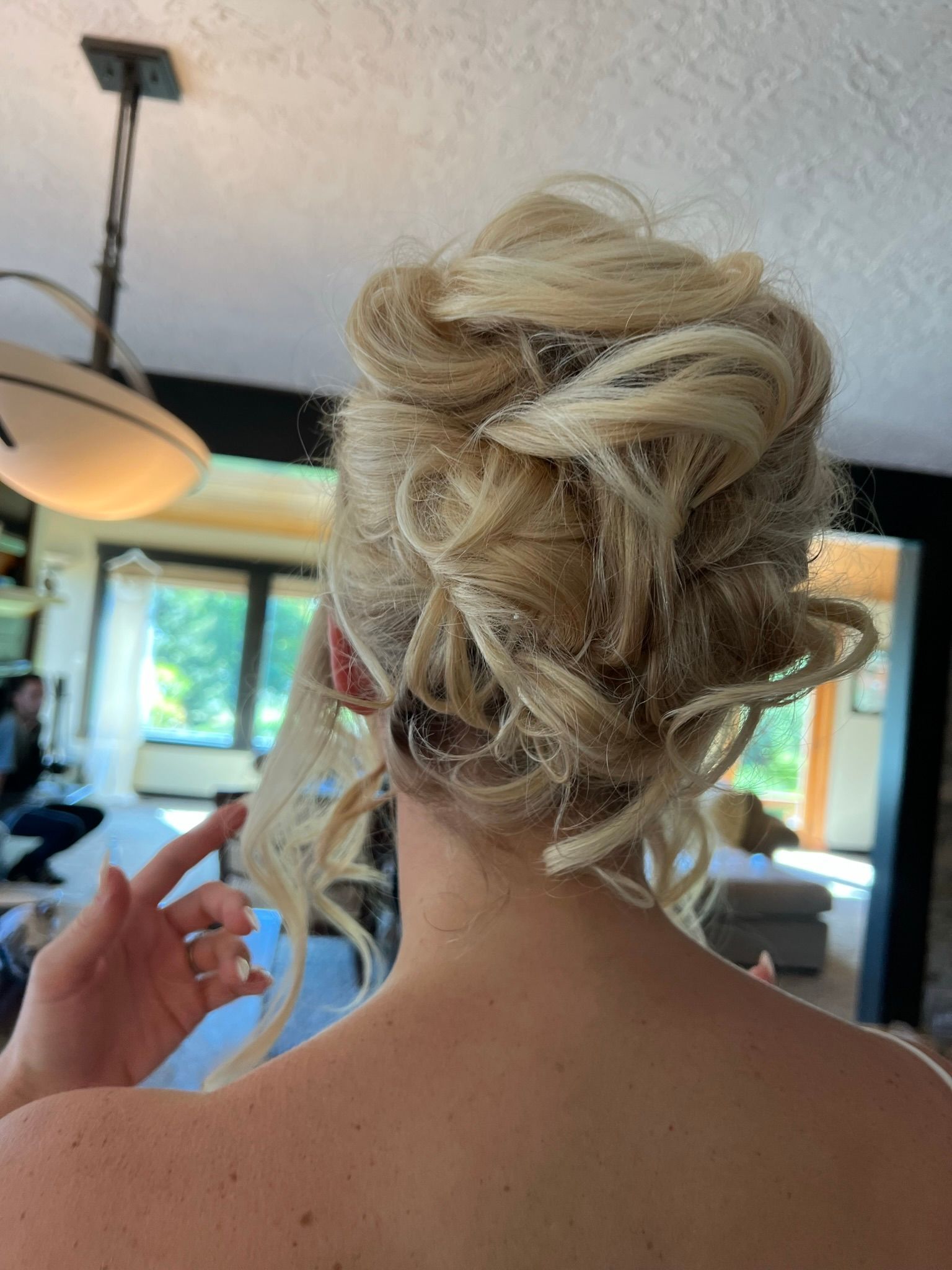 A woman with blonde hair in a messy bun is standing in a room.