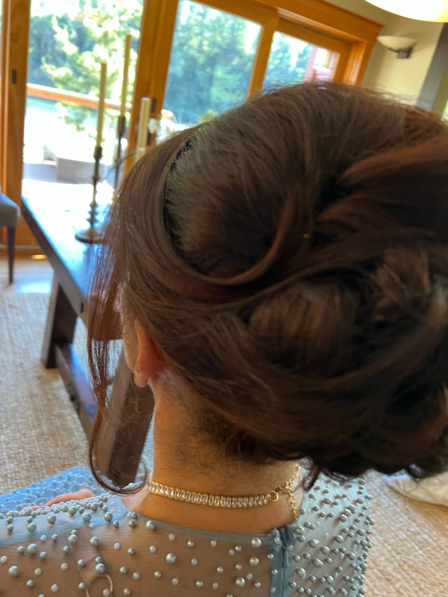 A woman 's hair is in a bun and she is wearing a necklace.