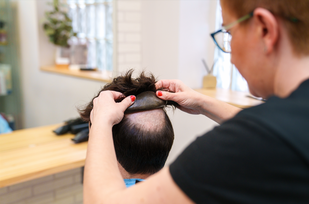 A woman is cutting a man 's hair in a salon.