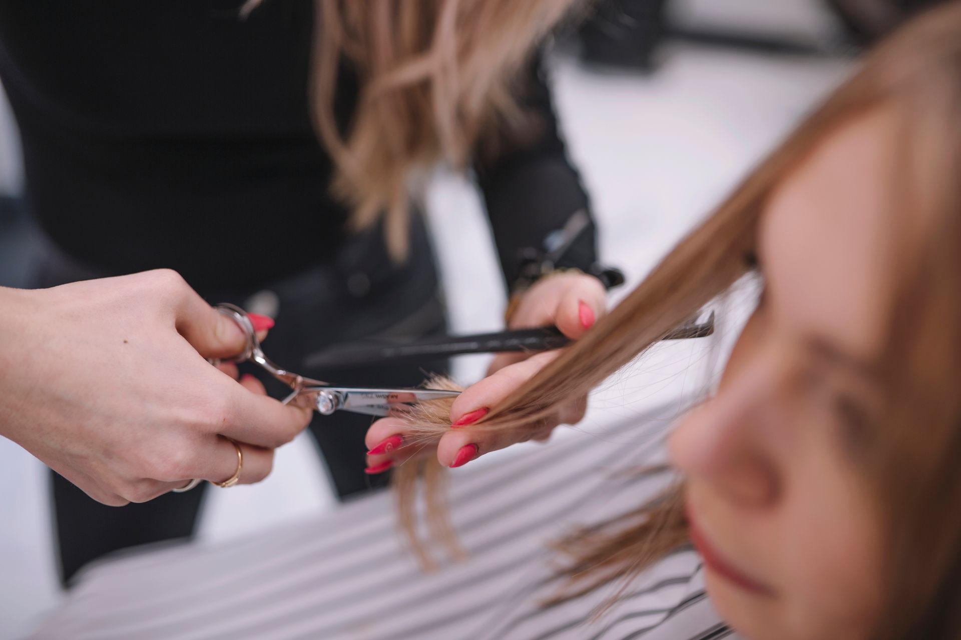 A woman is getting her hair cut by a hairdresser at a salon.