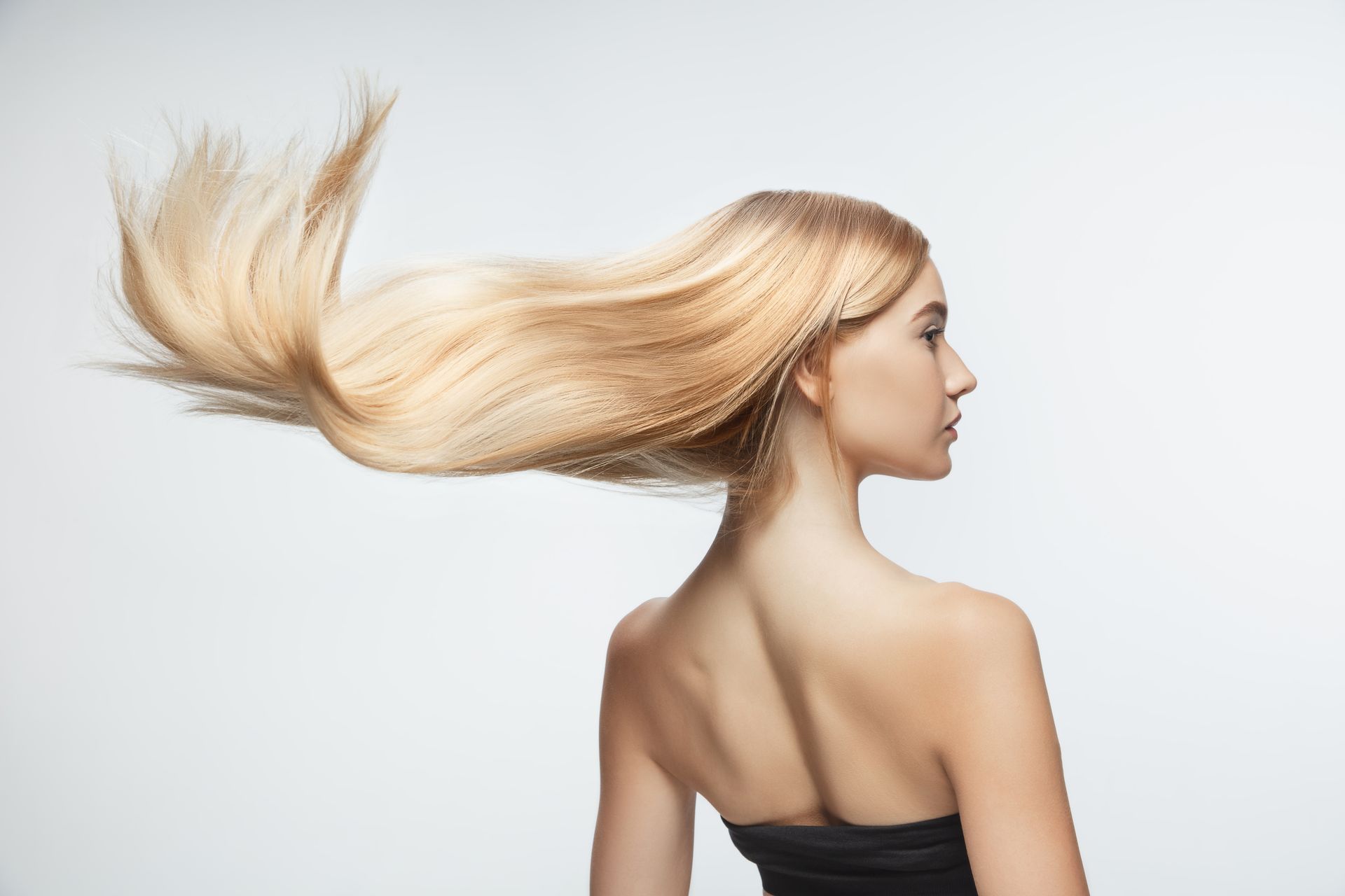 A woman with long blonde hair is standing in front of a black background.